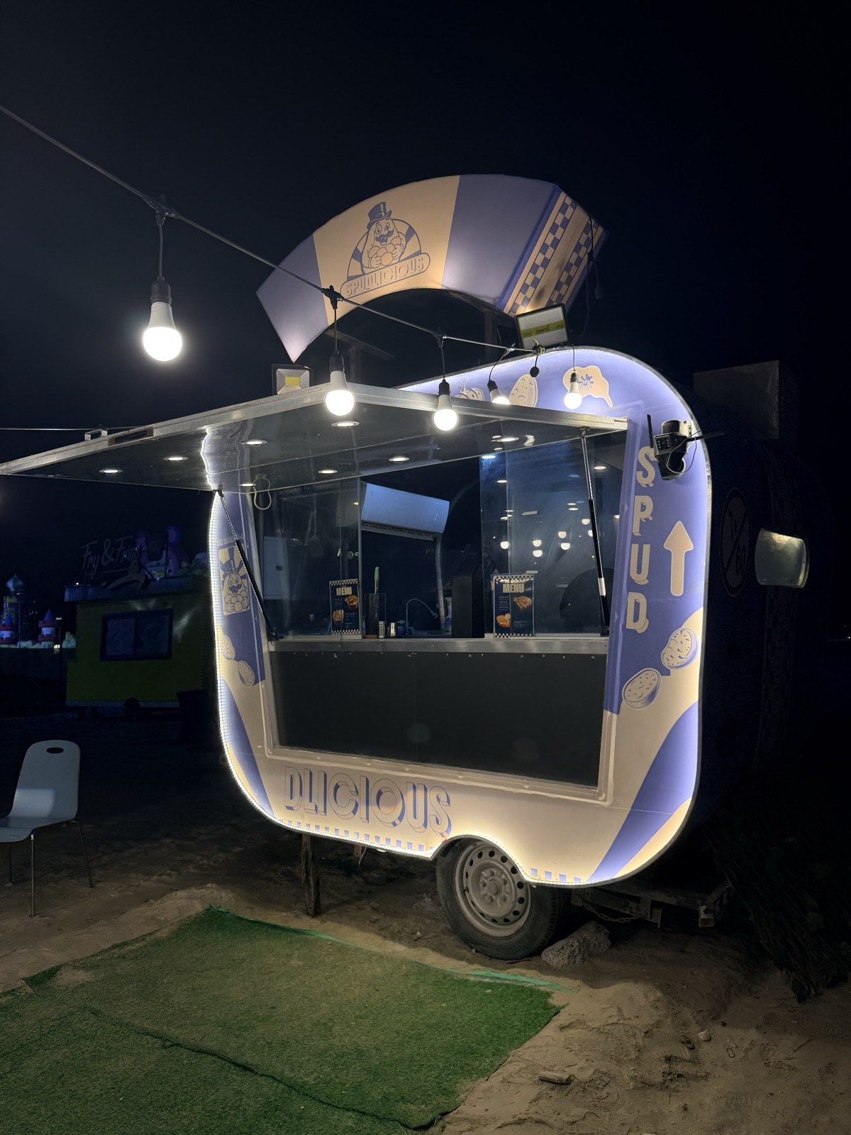 The Spudlicious food truck lit up under string lights at night — Busaiteen, Bahrain